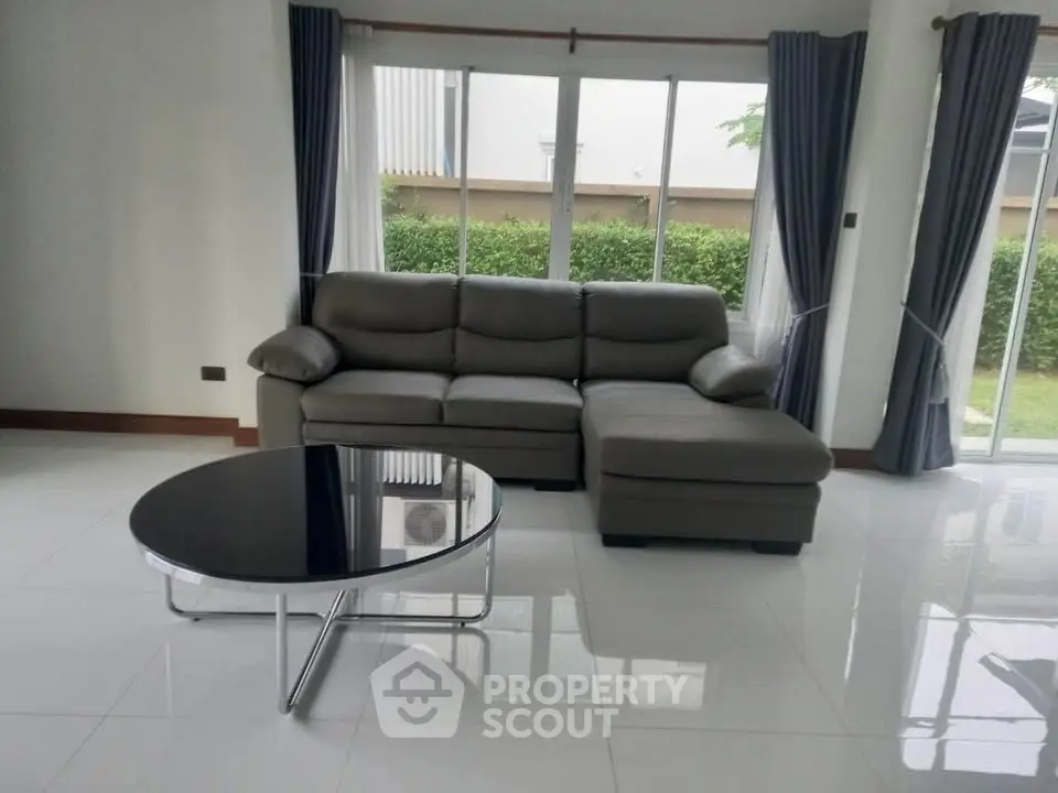 Spacious living room with modern sofa and garden view, perfect for relaxation.