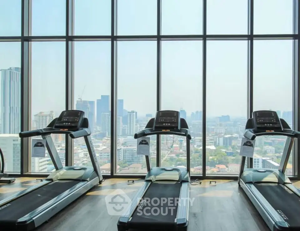 Spacious gym with panoramic city views and modern treadmills.