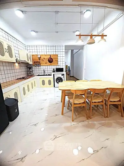 Modern kitchen with open layout, stylish dining area, and integrated washing machine.