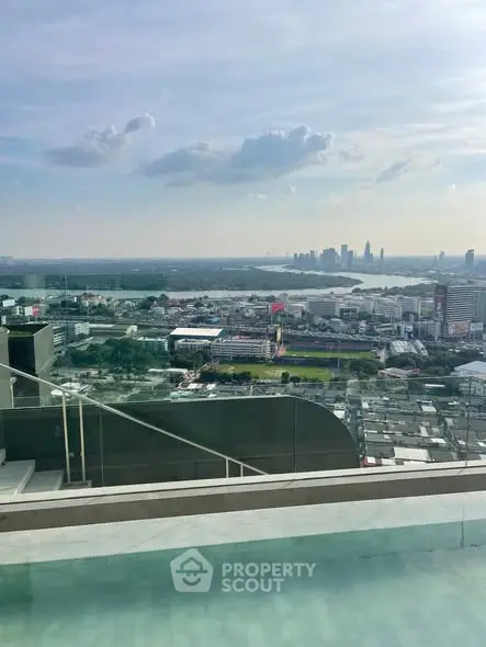 Stunning cityscape view from a high-rise balcony with glass railing and pool.