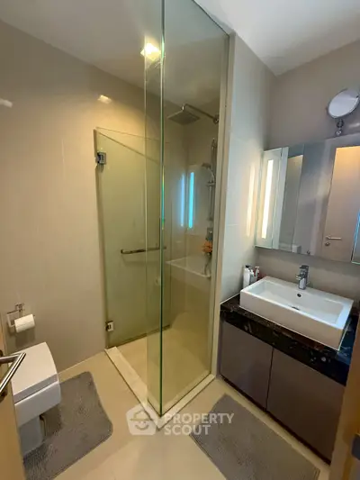 Modern bathroom with glass shower and sleek vanity in a contemporary apartment.
