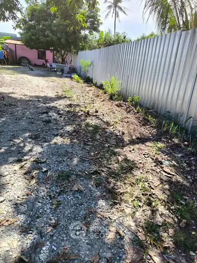 Spacious outdoor area with gravel path and metal fence, ideal for landscaping opportunities.
