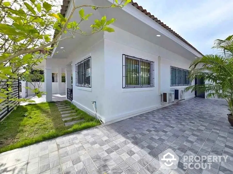 Charming single-story home with tiled patio and lush greenery, perfect for serene living.