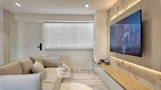 Modern living room with sleek design, featuring a wall-mounted TV and cozy seating area.