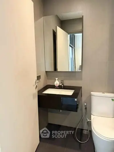 Modern bathroom with sleek fixtures and minimalist design, featuring a wall-mounted sink and mirror.