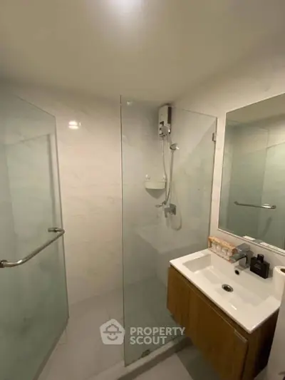 Modern bathroom with glass shower and sleek vanity in contemporary home.