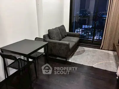 Modern living room with city view, featuring sleek furniture and floor-to-ceiling windows.