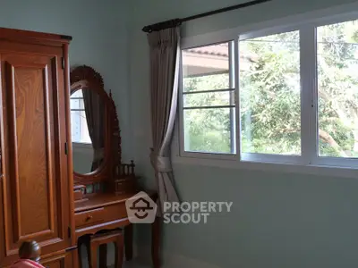 Charming bedroom with wooden furniture and large window offering lush garden views.