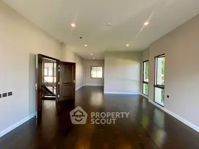 Spacious modern living room with dark wood flooring and large windows.