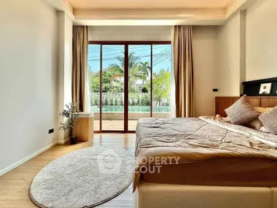 Spacious bedroom with large window and garden view, featuring elegant decor and natural light.