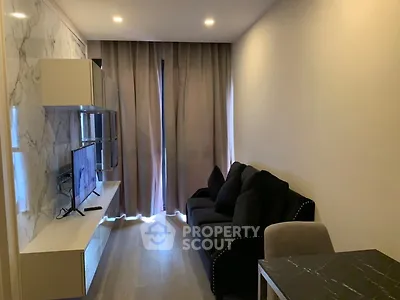 Modern living room with sleek marble wall, cozy black sofa, and mounted TV for stylish urban living.