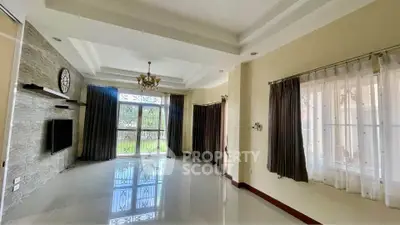 Spacious living room with elegant chandelier and large windows for natural light.