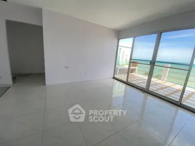 Spacious living room with ocean view and large balcony access, perfect for relaxation and entertaining.