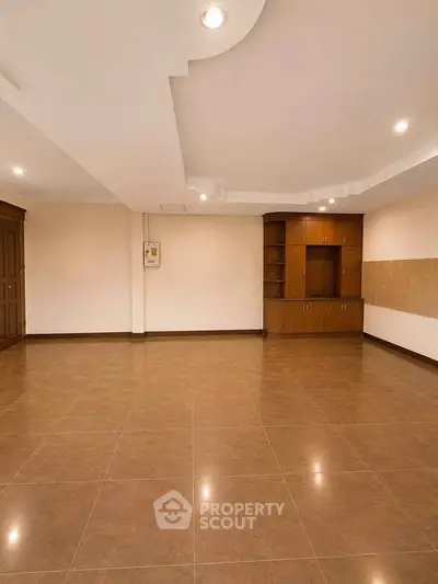 Spacious empty room with elegant wooden cabinetry and tiled flooring