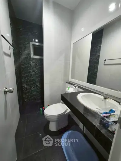 Modern bathroom with sleek black and white design, featuring a large mirror and contemporary fixtures.