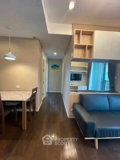 Modern living room with sleek furniture and dining area, featuring hardwood floors and stylish lighting.