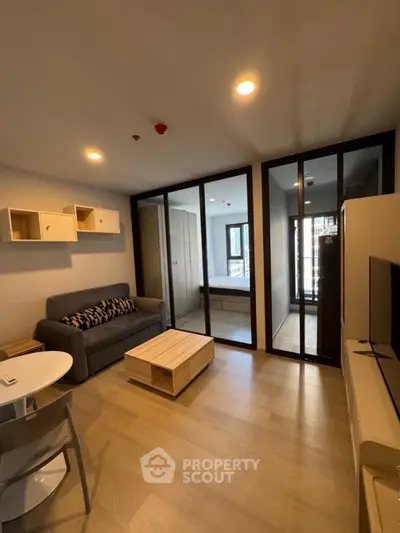 Modern living room with stylish furniture and glass partition leading to bedroom