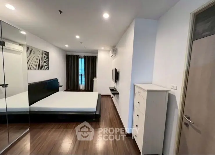 Spacious modern bedroom with mirrored closet and sleek wooden flooring