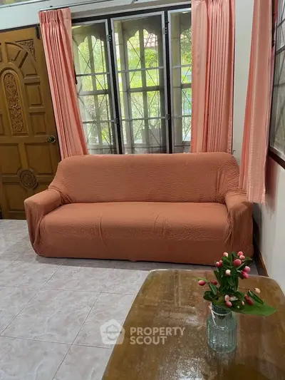 Cozy living room with peach sofa and floral decor, perfect for relaxation.