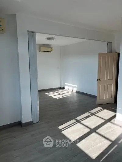 Spacious sunlit room with modern flooring and air conditioning, perfect for versatile living space.