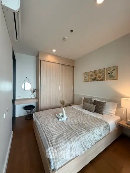 Modern bedroom with stylish decor and ample natural light, featuring a cozy bed and elegant wooden wardrobe.