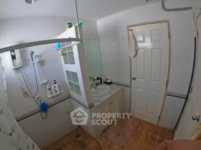 Spacious bathroom with modern shower and sink area, featuring tiled walls and floor.