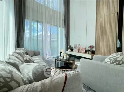 Luxurious living room with high ceilings and elegant decor, featuring large windows and plush seating.