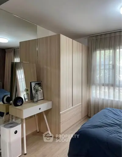 Modern bedroom with stylish decor and natural light, featuring a sleek wardrobe and elegant furnishings.
