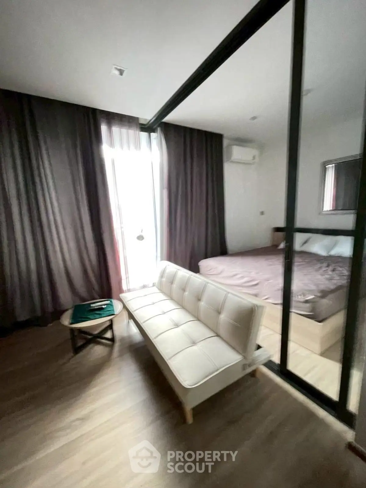 Modern studio apartment with cozy living area and bedroom, featuring large windows and stylish decor.