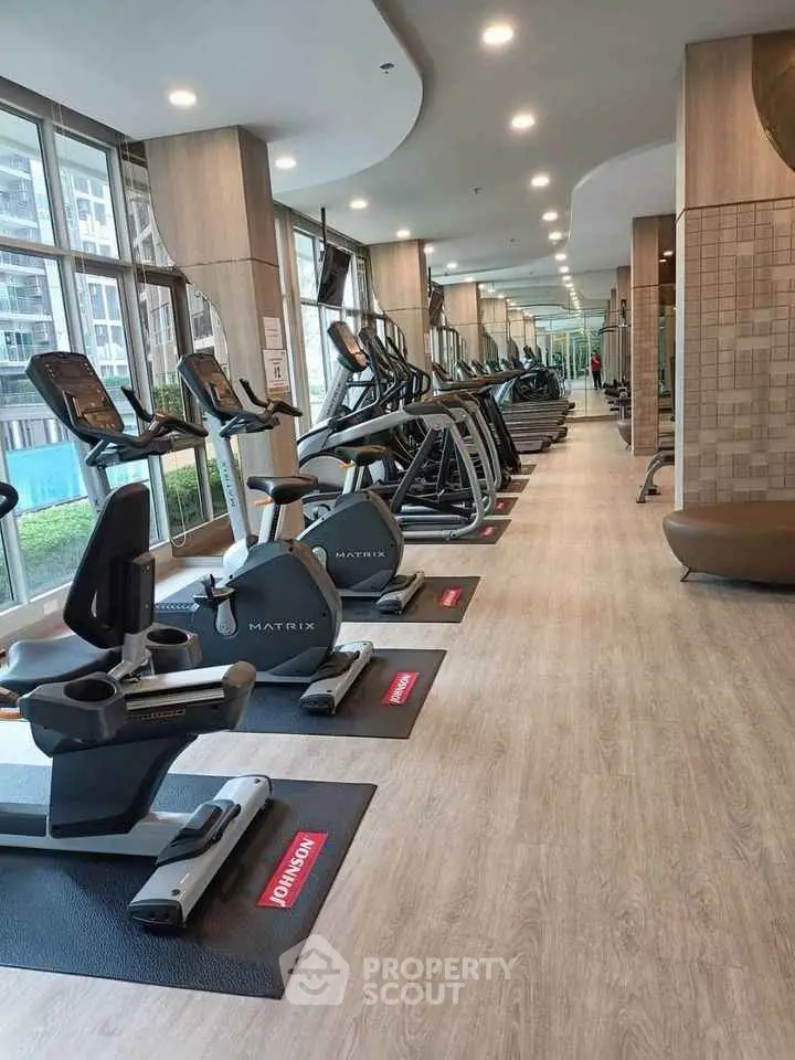 Modern gym with state-of-the-art equipment and large windows in luxury residential building.