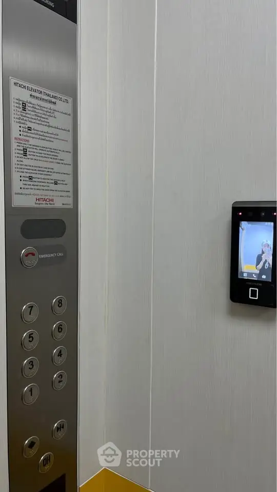 Modern elevator interior with control panel and digital screen in a residential building.