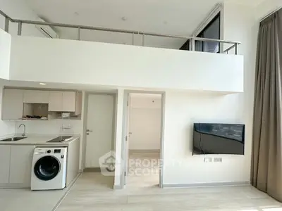 Modern loft apartment with mezzanine, sleek kitchen, and wall-mounted TV, offering a stylish urban living space.