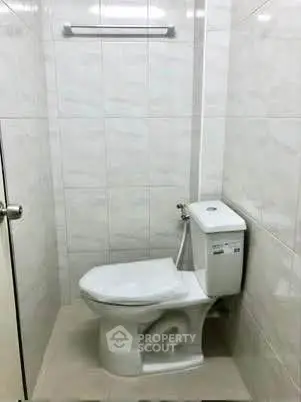 Compact bathroom with modern toilet and tiled walls, ideal for efficient space utilization.