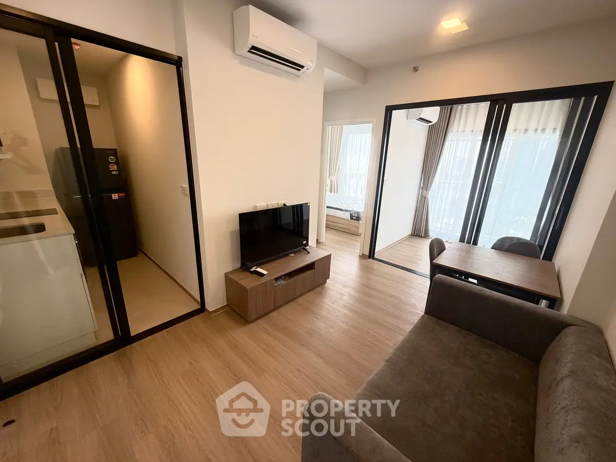 Modern apartment interior with open layout, featuring a cozy living area and dining space with large windows.