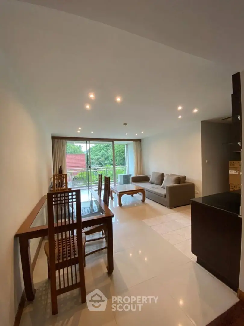 Spacious living room with modern furniture and large windows opening to a balcony with a view.