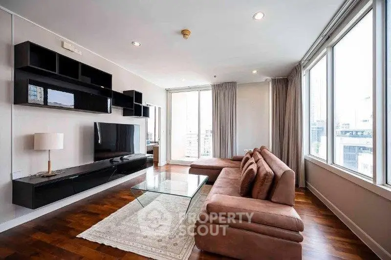 Spacious modern living room with large windows and stylish furniture in a high-rise apartment.