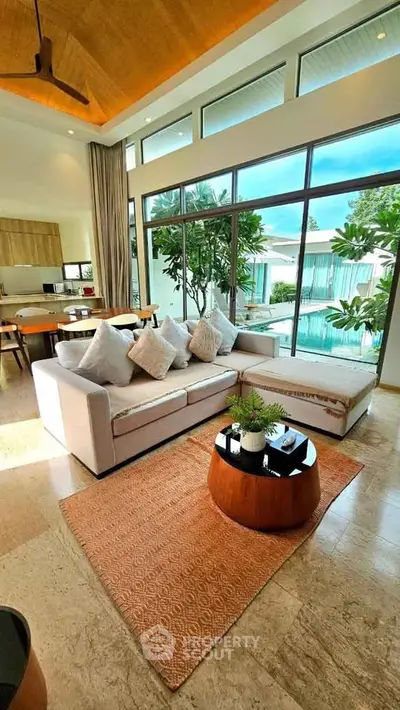 Luxurious living room with pool view, high ceilings, and elegant decor in a modern home.