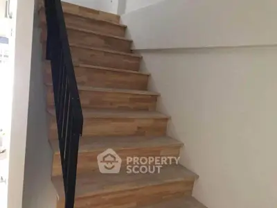 Modern wooden staircase with sleek black railing in a contemporary home interior.