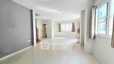 Spacious and bright living area with large windows and neutral decor.