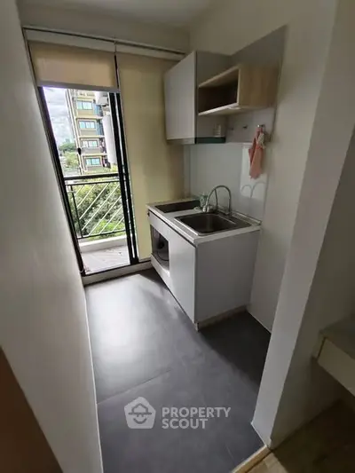 Compact modern kitchen with balcony view in urban apartment
