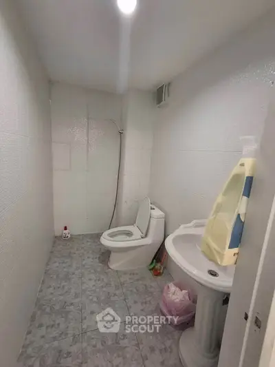 Compact bathroom with white tiles and basic fixtures, ideal for small spaces.