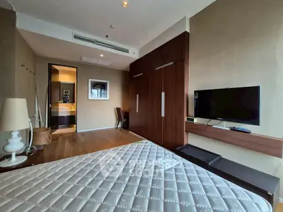 Spacious bedroom with modern furnishings and wall-mounted TV in a luxury apartment.