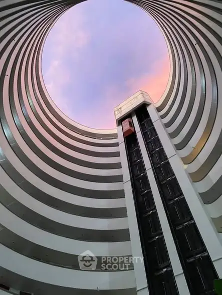 Stunning architectural view of a modern building's circular atrium with elevator and sky view.
