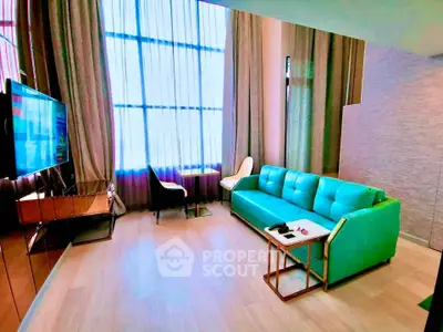 Modern living room with teal sofa, wall-mounted TV, and large windows with elegant curtains.