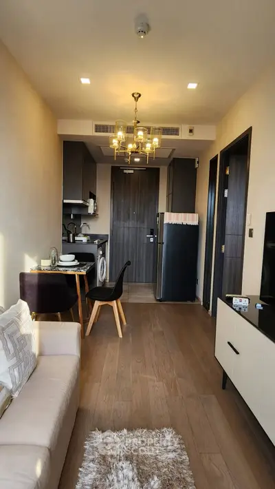 Modern apartment interior with open kitchen and cozy living area, featuring elegant lighting and stylish furniture.