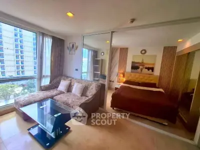Modern studio apartment with cozy living area and bedroom, featuring large windows and stylish decor.