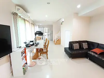 Spacious modern living room with sleek black sofa and dining area, perfect for family gatherings.