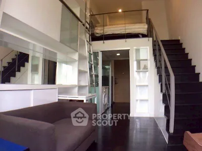 Modern loft apartment with mezzanine bedroom and sleek black staircase.