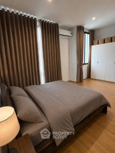 Spacious bedroom with modern decor and ample natural light, featuring a cozy bed and stylish curtains.