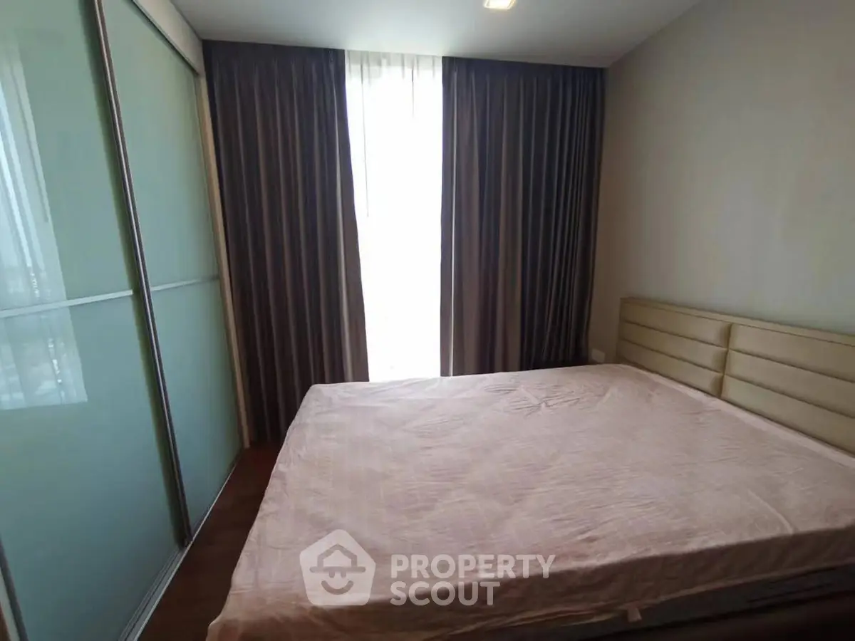 Cozy bedroom with large window and modern sliding wardrobe in a stylish apartment.